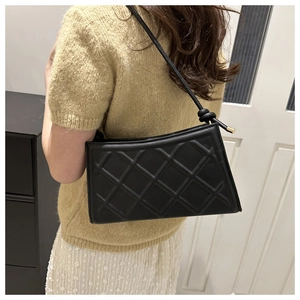 Détail du sac bandoulière en cuir noir matelassé avec bandoulière nouée et détails dorés