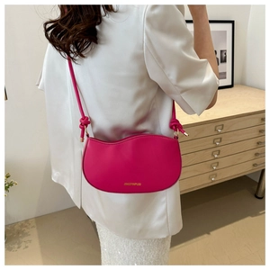 Detailed view of hot pink crescent bag with knot strap on a white blazer model