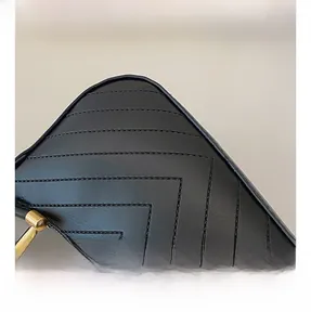 Detail shot of black leather bag with V-shaped chevron quilting and golden zipper hardware
