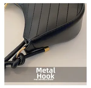 Detail of matte black leather handbag with vertical quilting and gold metal hook hardware