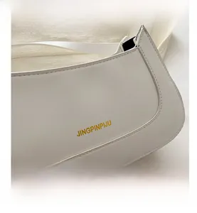 Close-up of white faux leather bag with golden letter printing and precise double stitching