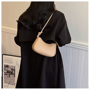 Detail of chevron quilted hobo bag in cream beige worn over a black wool coat