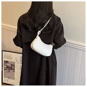 Detail of white quilted hobo bag with gold metal rings and minimalist stitch texture