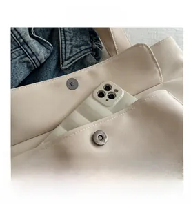 Détail du sac cabas en toile beige avec fermoir magnétique et poche frontale pour téléphone