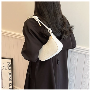 Detail of beige quilted shoulder bag with V-pattern stitching and knot strap detail