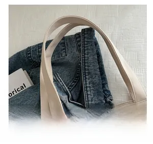 Gros plan des poignées larges d'un sac cabas en toile beige avec détails de couture précis