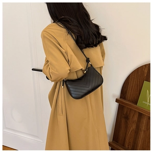 Detail of black quilted faux leather shoulder bag with V-shaped stitching and gold hardware