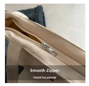 Détail de la fermeture éclair argentée sur un grand sac cabas en toile de couleur crème