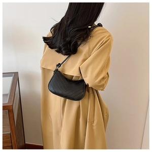 Detail of black V-quilted faux leather shoulder bag with decorative knotted strap detail
