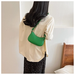 Detail showing the green crescent underarm bag with unique knot design on shoulder strap