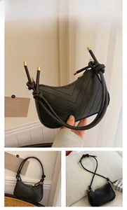 Detail of black V-quilted shoulder bag with glossy finish and decorative knotted strap
