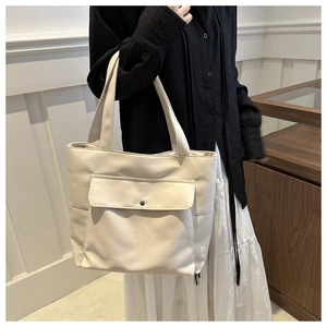 Gros plan d'un sac cabas en toile crème avec grande poche avant à rabat et poches latérales