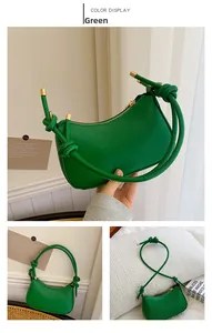 Detail view of green crescent shoulder bag with V-quilted pattern and knot handle design
