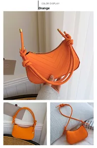 Detail of orange crescent underarm bag with V-shaped quilting and knotted shoulder strap