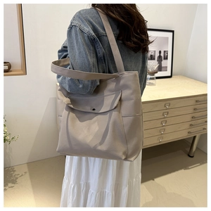 Vue détaillée d'un grand sac fourre-tout gris clair porté à l'épaule pour le quotidien