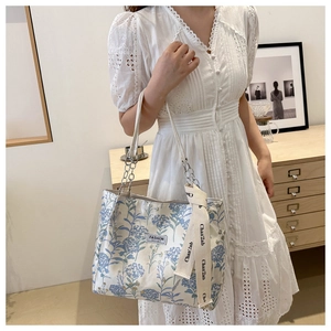 Sac fourre-tout à fleurs avec chaîne argentée et ruban sur une robe en dentelle