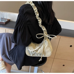 Détail du sac plissé vert menthe avec chaîne en perles et nœud décoratif élégant