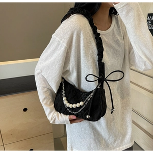 Détail d'un sac à bandoulière noir froncé avec des perles et une chaîne en métal argenté