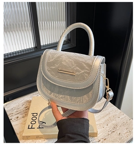 Detailed shot of wrinkled leather saddle bag with gold metal buckle and round handle