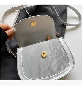 Detail of silver pleated texture handbag with gold magnetic clasp and slim shoulder strap