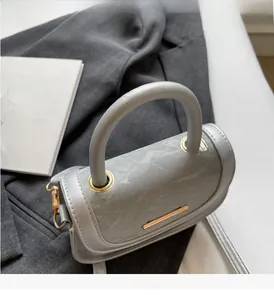 Detail of grey saddle bag featuring marble texture lid and elegant gold metal buckles