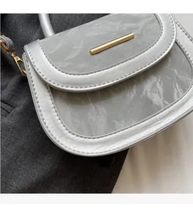 Close-up of silver-grey saddle bag with marble texture and gold metallic hardware