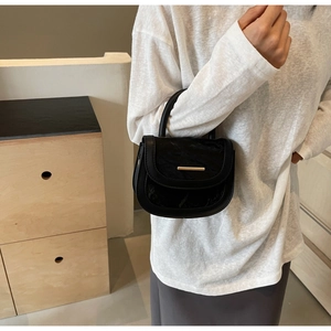 Detail of black saddle bag with gold bar and cloud texture fold on the flap