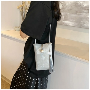 Detailed view of silver crossbody phone bag with pearl, tassel and cloud charm decor