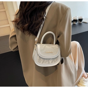 Model wearing a metallic saddle crossbody bag against a minimalist cafe background
