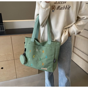 Detail of dark green canvas tote with colorful embroidery and matching round coin purse