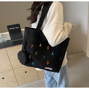 Detail of black canvas tote with colorful towel embroidery and mini hanging purse