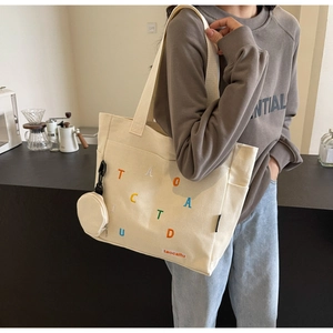 Détail d'un cabas en toile avec broderie de lettres colorées et mini-pochette