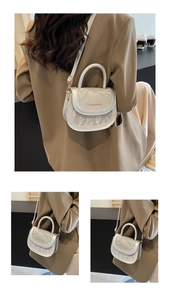 Detail of silver saddle bag with metallic pleated texture and gold metal buckle