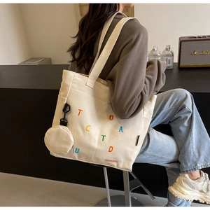 Détail du sac cabas en toile avec broderie colorée et petit porte-monnaie détachable