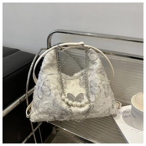 Detail of white butterfly hobo bag with fringe texture, pearl charms and metal chains
