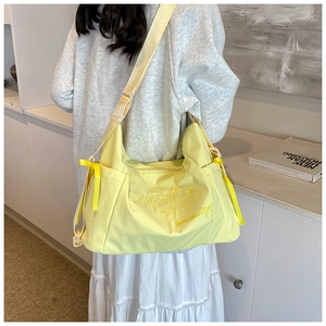 Close-up of yellow canvas tote bag featuring embroidered text and a side ribbon bow
