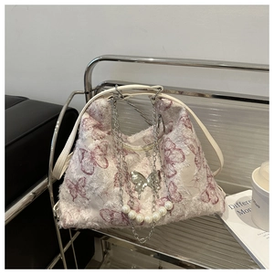 Detail of white butterfly tote bag featuring silver chain, pearl charms and tassel edges