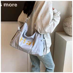 Detail of light purple nylon tote bag with yellow Hai embroidery and drawstring side