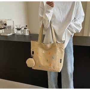 Large beige canvas tote bag with colorful letter embroidery and matching small round pouch