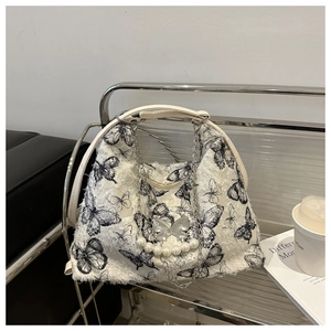 Detail of white plush tote bag featuring black butterfly prints and pearl pendants