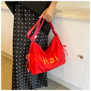 Detail of red nylon shoulder bag with yellow Hai embroidery and side ribbon drawstring