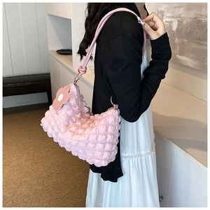 Detail of pink puff cloud shoulder bag featuring quilted texture and floral charm accessory