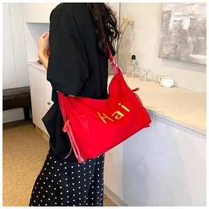Close-up of red nylon tote bag featuring yellow Hai embroidery and drawstring details