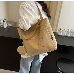 Detail of khaki canvas tote bag with colorful embroidery and mini coin purse charm