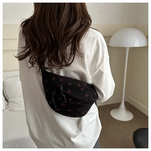 Détail du sac besace en velours côtelé noir à motifs fraises porté en bandoulière