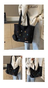 Vue détaillée du grand sac cabas en toile noire avec broderie colorée et poche latérale