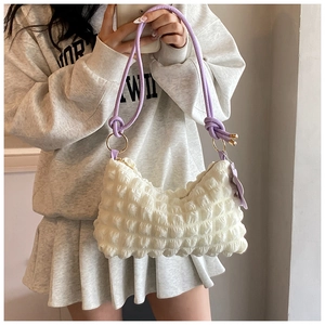 Detailed view of white bubble texture fabric with purple handle and flower charm