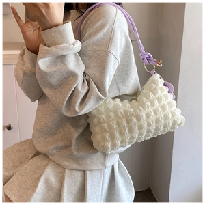 Detail of white puff bag with popcorn texture and contrasting lilac shoulder strap