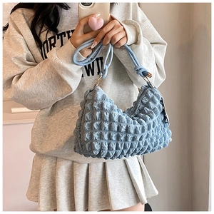 Close-up of light blue bubble textured nylon bag with gold metal rings and zipper