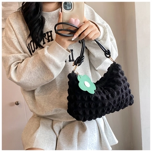 Detail of black puff cloud bag featuring quilted texture and green flower charm